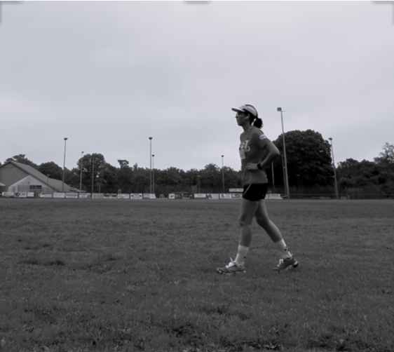 Sportive en mouvement sur un terrain, photographiée en noir et blanc.